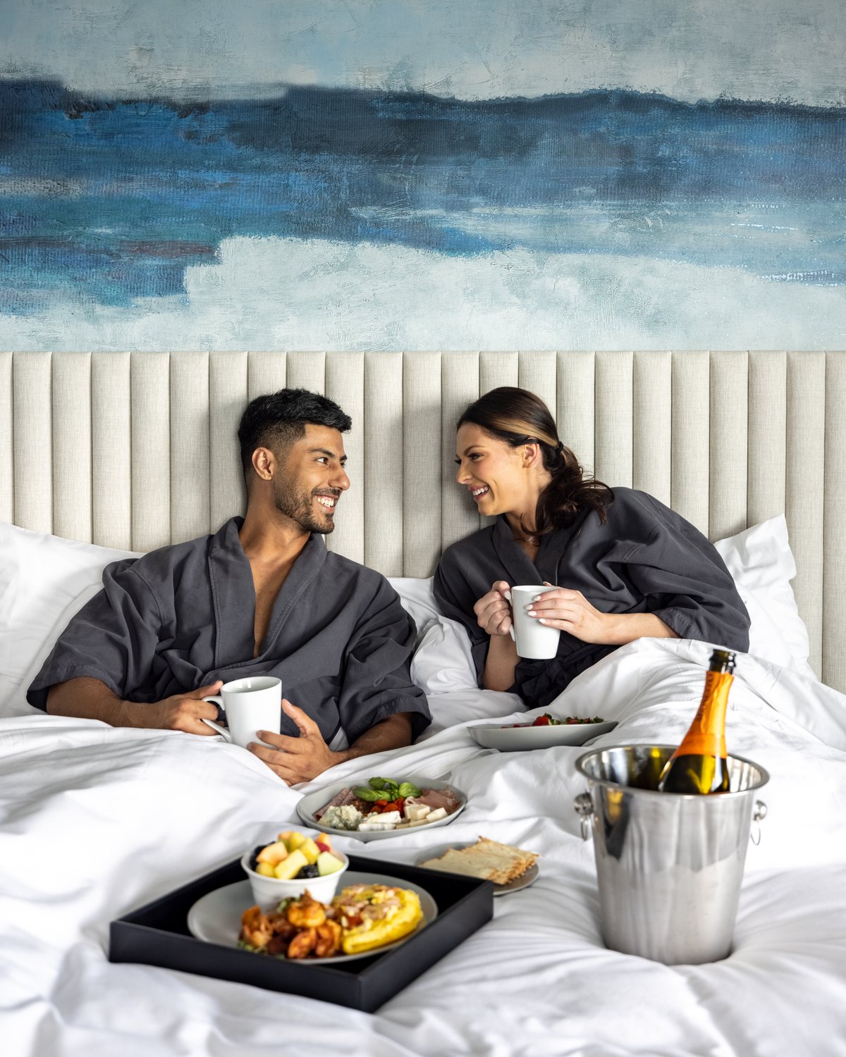 Guests in robes sharing breakfast in bed at a hotel