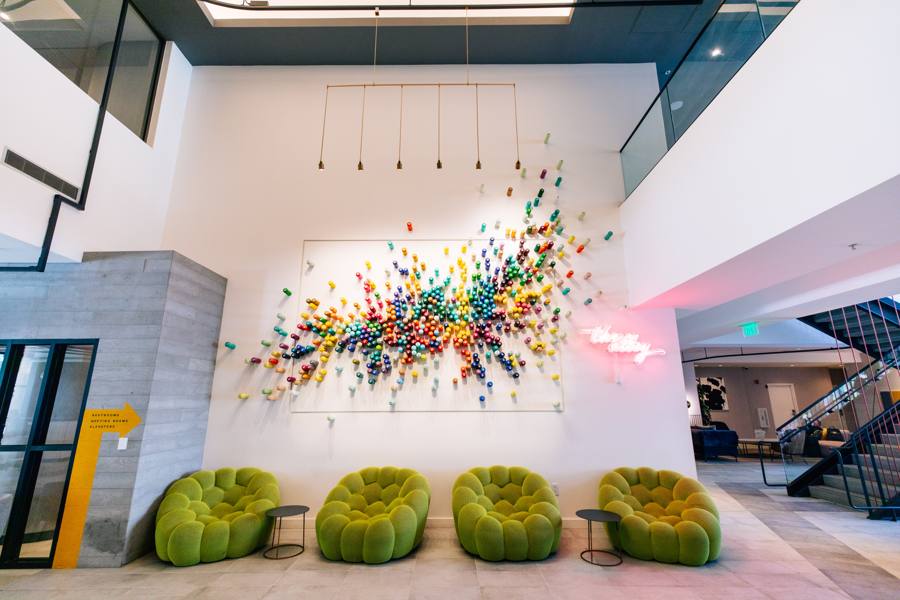 Colorful paint-can art wall and green lounge chairs in the lobby at The Clancy